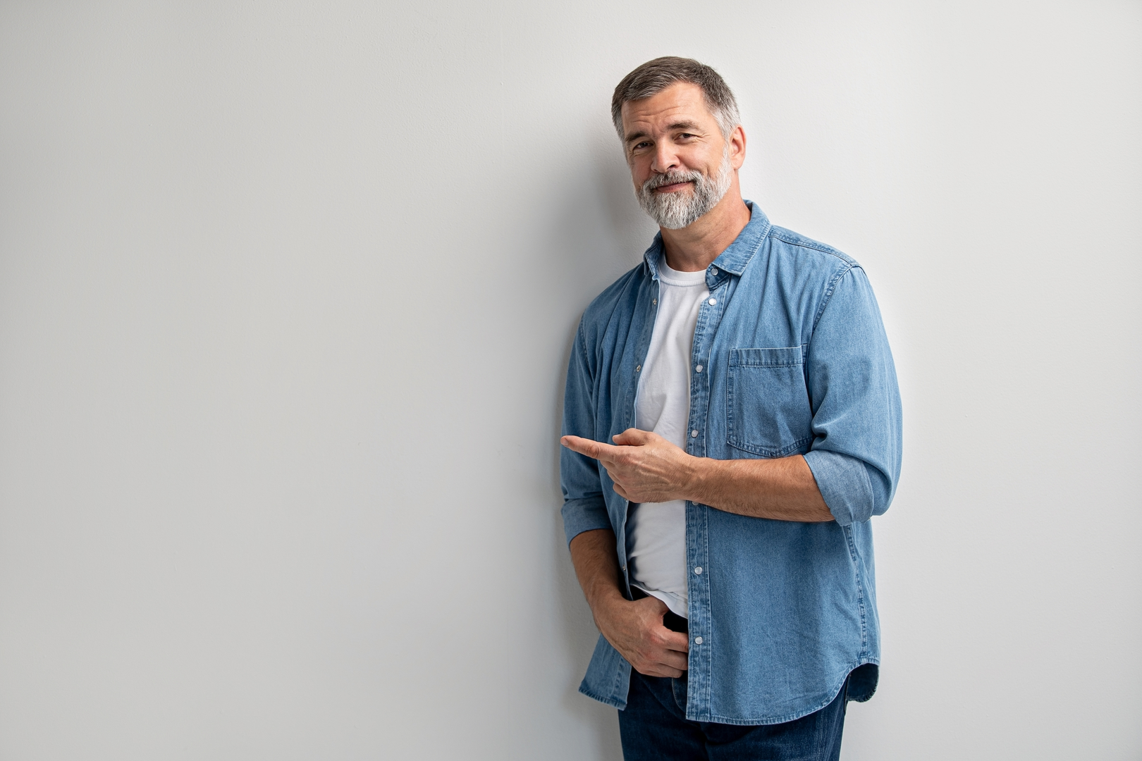 Muž staršího věku v modré košili ukazuje prstem doleva